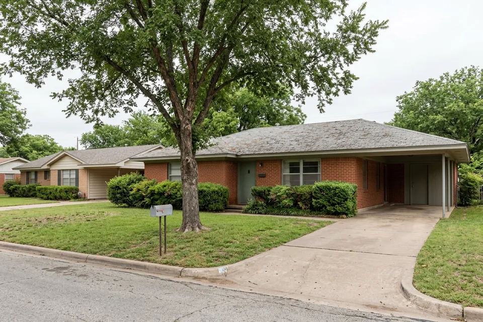 Illustration of a 1960s red brick ranch house with a carport